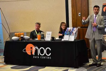 Sponsor exhibit booth at Tech Valley Cybersecurity Symposium, with INOC Data Centers signage and attendees